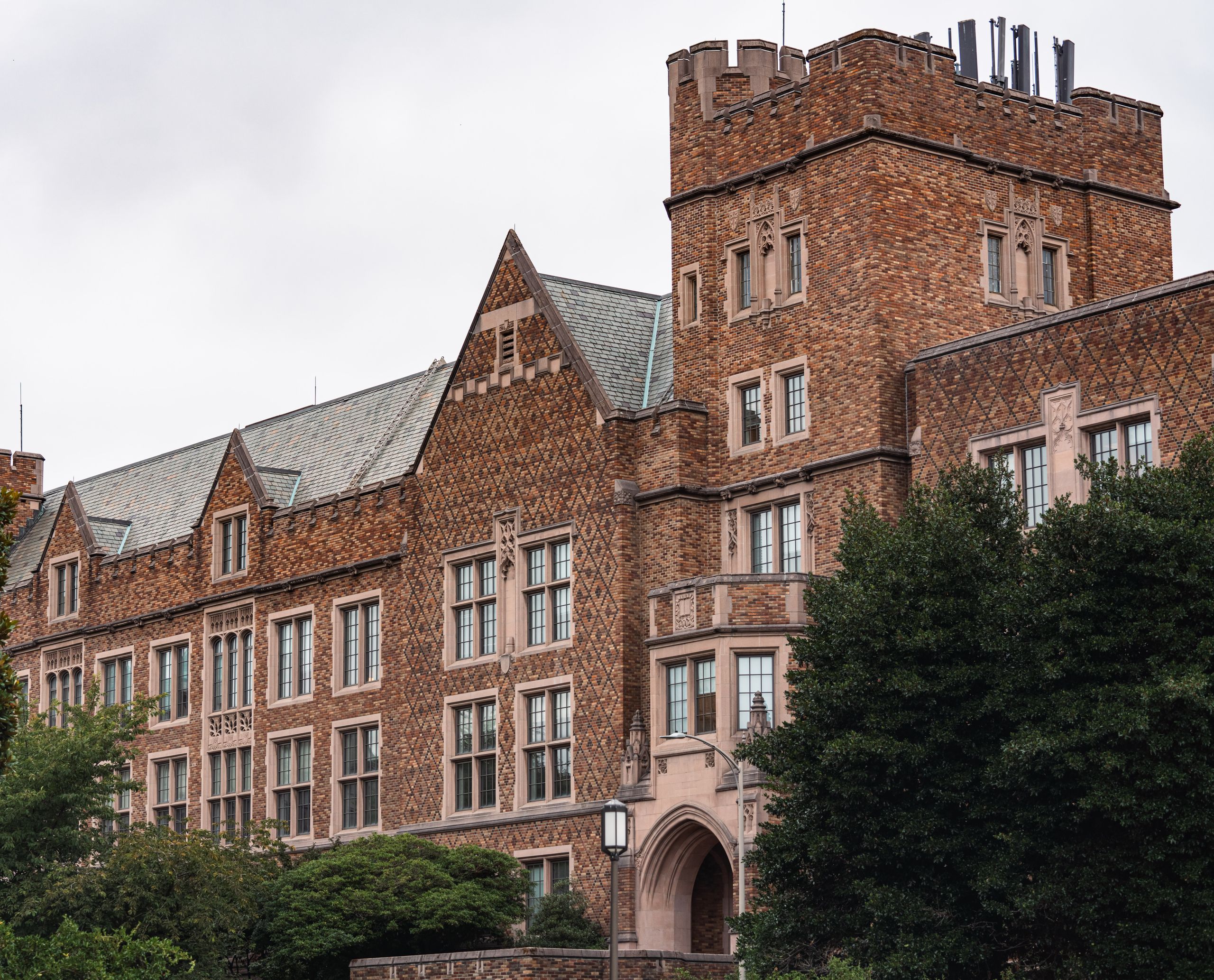 Majestic brick university building with lush greenery. Classic architectural design showcasing large windows.